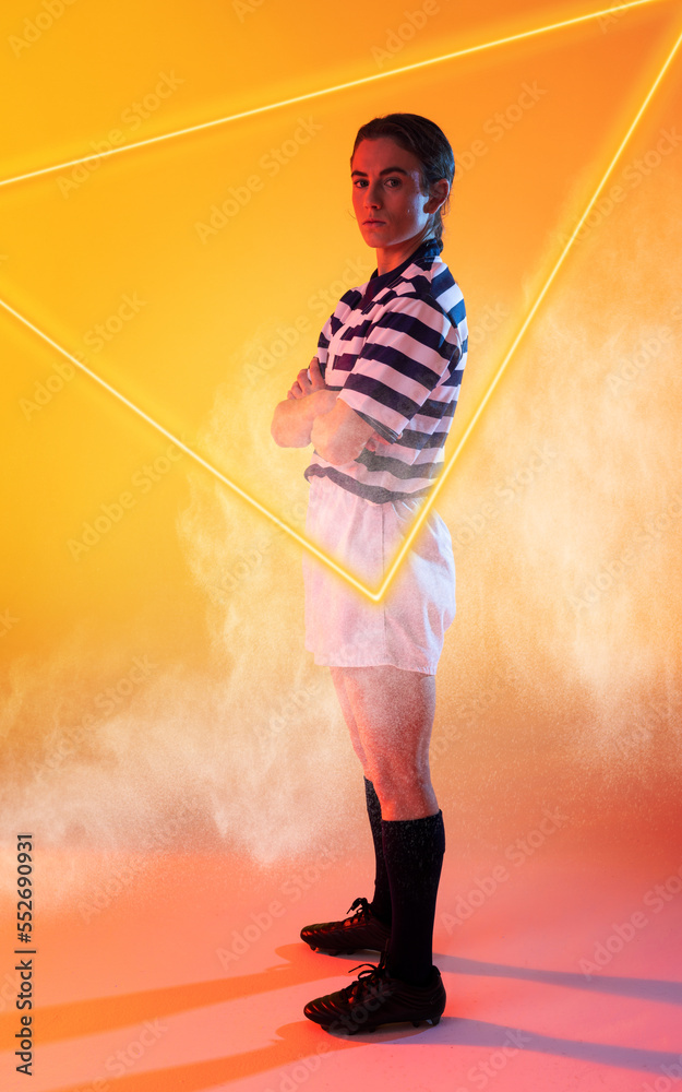 Confident caucasian female rugby player with arms crossed standing by illuminated triangle