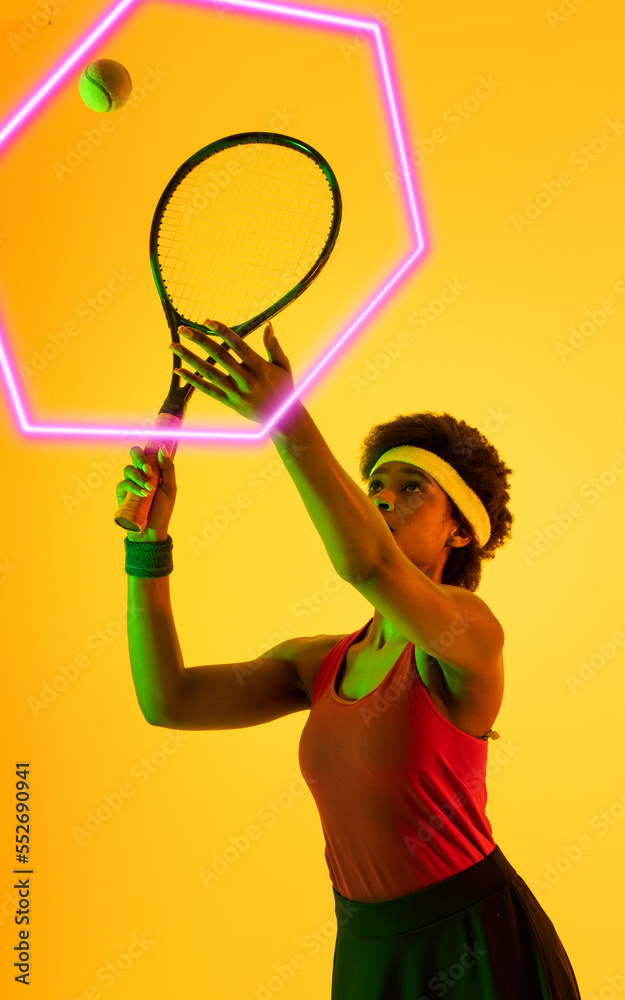 African american tennis female player hitting ball with racket by illuminated hexagon, copy space