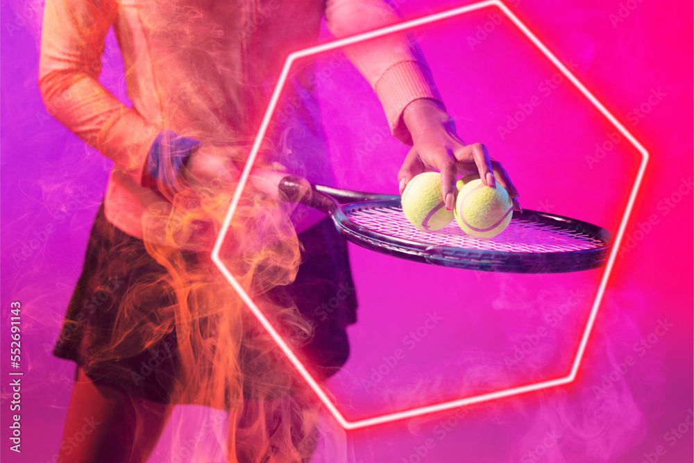 Midsection of african american female tennis player placing balls on racket by illuminated hexagon