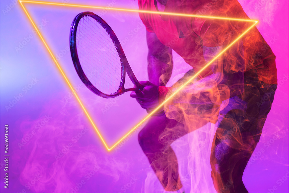 Midsection of african american male tennis player holding racket by red illuminated triangle