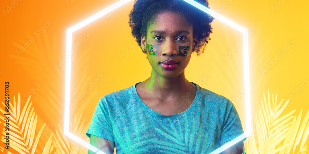 Portrait of african american female fan with brazilian face paint by illuminated hexagon and plants