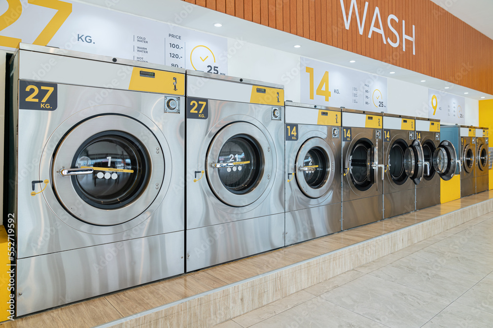 A row of qualified coin-operated washing machines in a public store. Concept of a self service comme