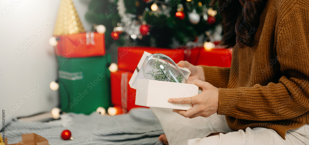 Merry Christmas Hands Hands opening christmas gift with red bow on background of christmas tree with