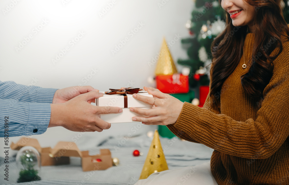 圣诞礼物在手。快乐男人在家送圣诞和新年礼盒给女人。X家人