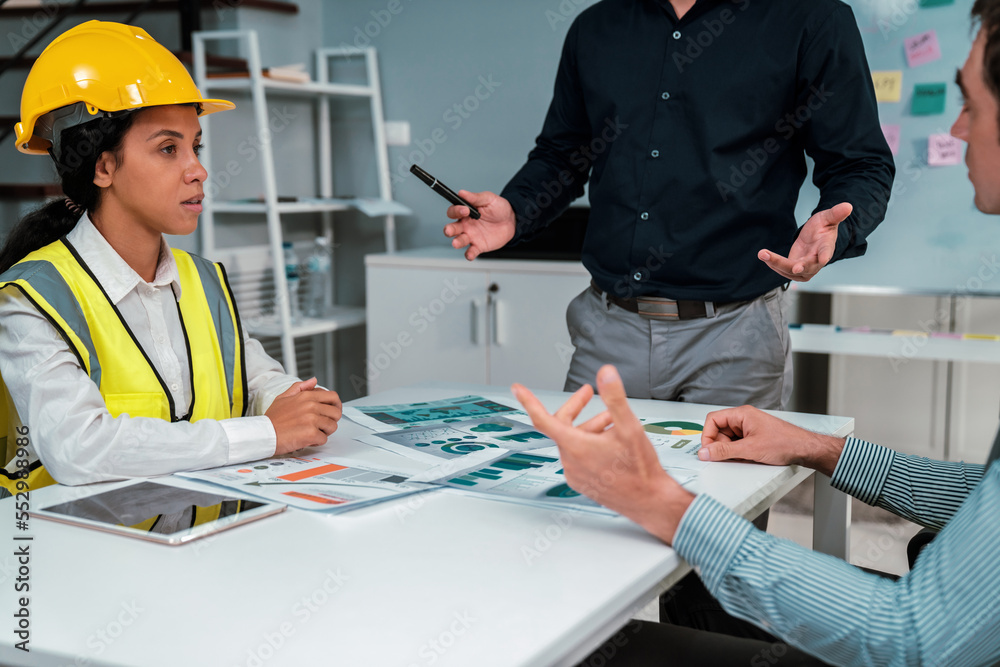 Engineers and competent employer discussing plans and blueprints together with tablet in the office.