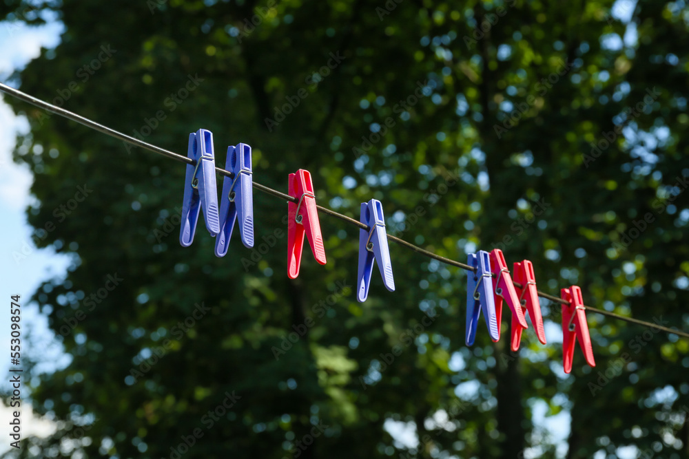 Many colorful clothespins hanging on rope outdoors