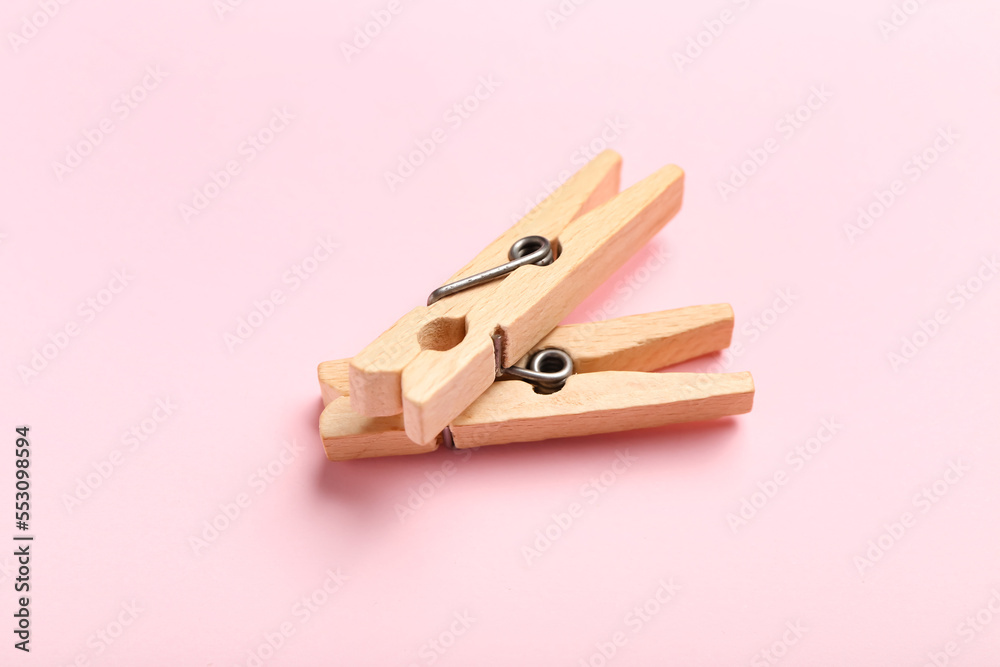 Two wooden clothespins on pink background