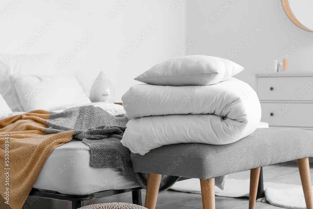 Folded white blanket and pillow on bench in bedroom