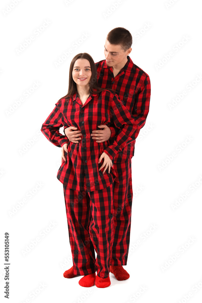 Young couple in checkered pajamas on white background