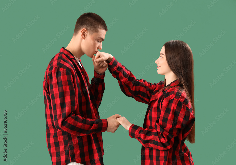 Young couple in checkered pajamas on green background