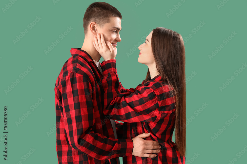 Young couple in checkered pajamas on green background