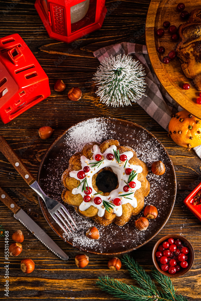 Composition with tasty Christmas cake, hazelnuts, cranberry and decorations on wooden background