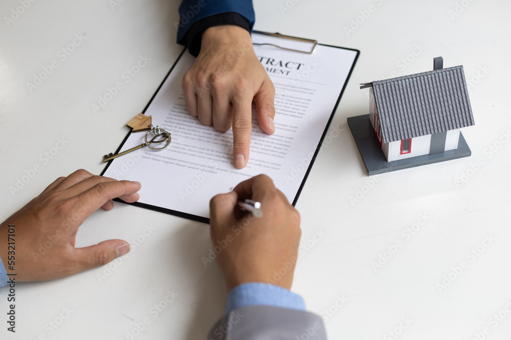 Businessmen and real estate agents sign contracts to legally sell homes.