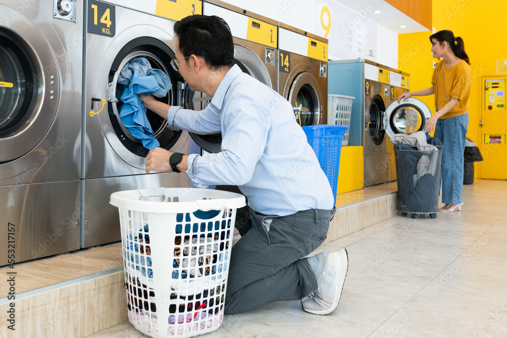 Asian people using qualified coin operated laundry machine in the public room to wash their cloths. 