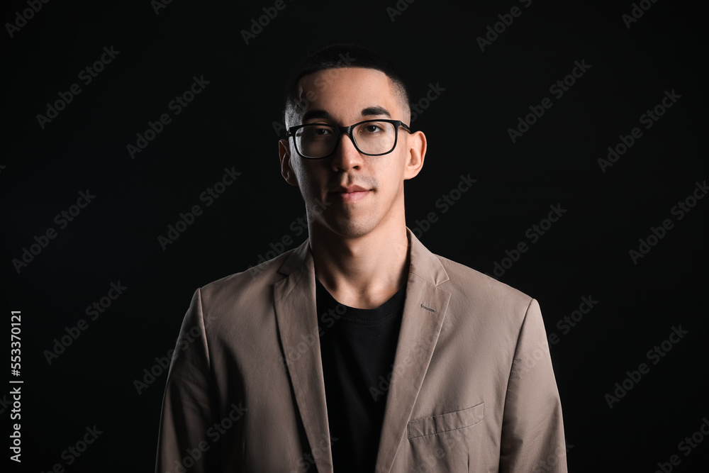 Portrait of young Asian man wearing eyeglasses on black background