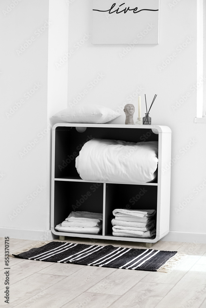 Shelving unit with bed sheets near light wall