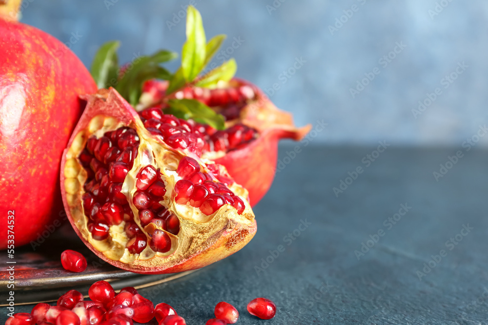 Plate of fresh pomegranates on color background, closeup