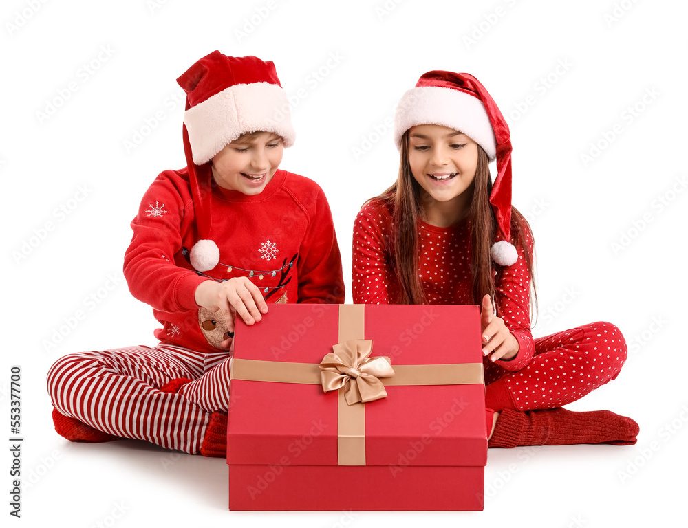 Little children in Santa hats opening Christmas gift on white background