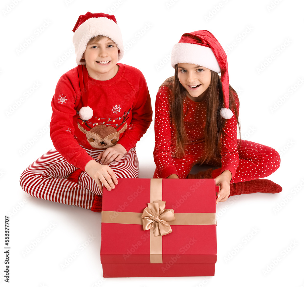 Little children in Santa hats opening Christmas gift on white background