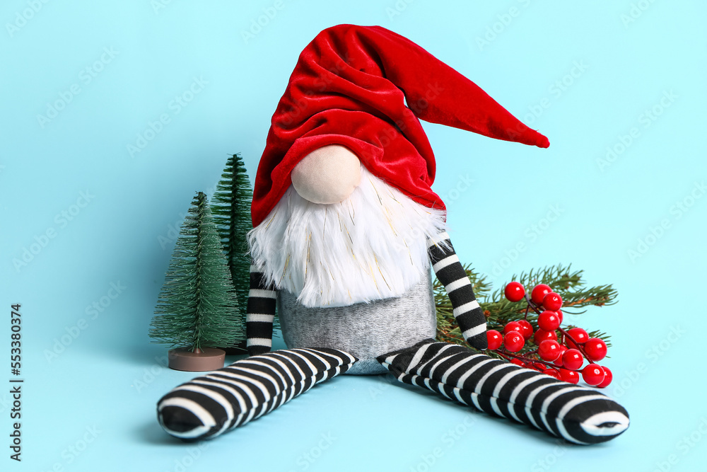 Christmas gnome, fir branches and decorations on color background