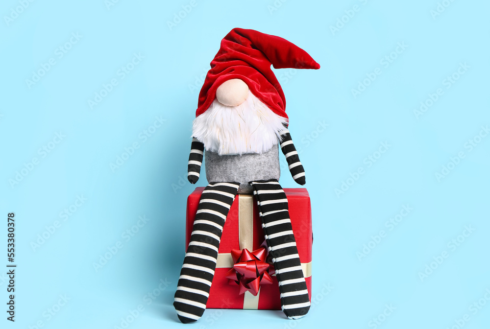 Christmas gnome on gift box against color background