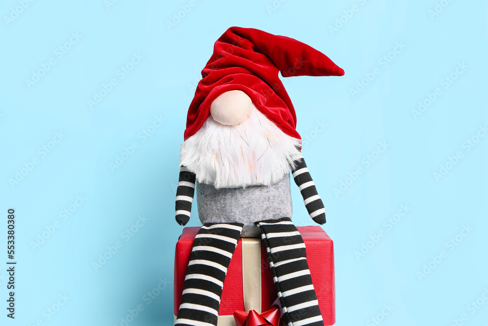 Christmas gnome on gift box against color background