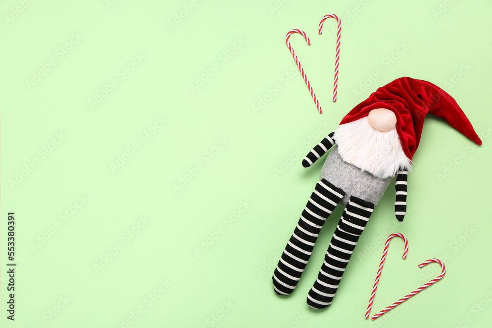 Christmas gnome and candy canes on green background