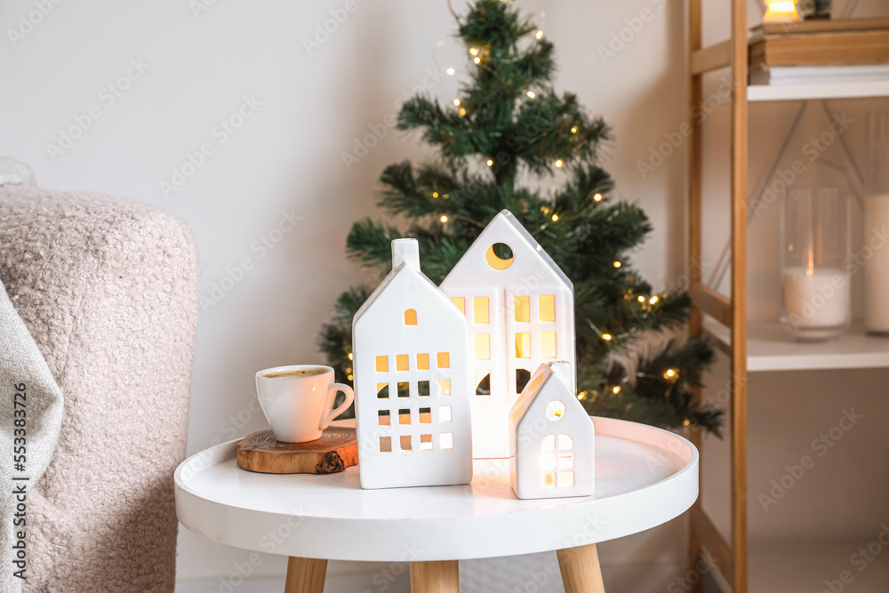 House shaped candle holders and cup of coffee on table in living room, closeup