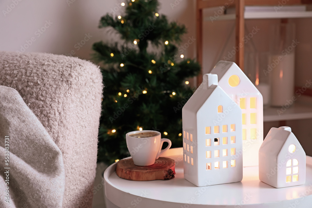 House shaped candle holders and cup of coffee on table in living room, closeup