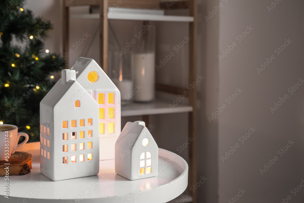 House shaped candle holders and cup of coffee on table in living room, closeup