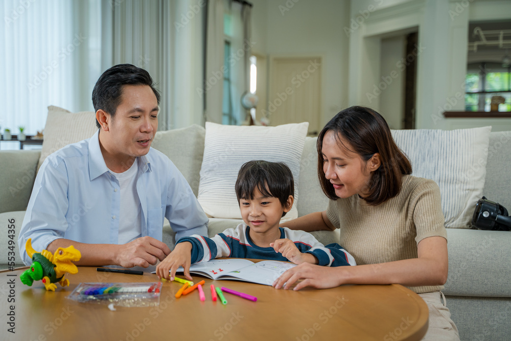 Son doing his homework with mother in living room at home,Child and parent drawing together.