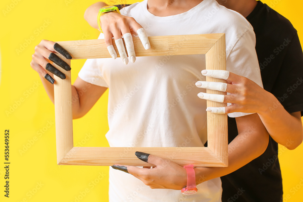 Women holding wooden frame on color background, closeup