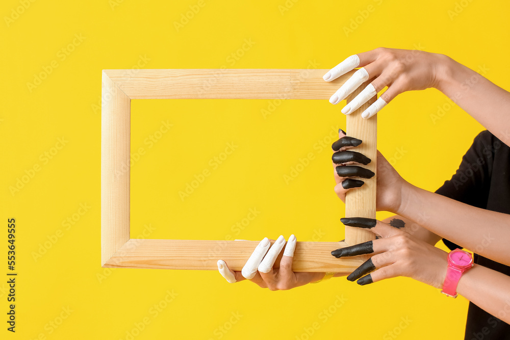 Female hands with wooden frame on color background