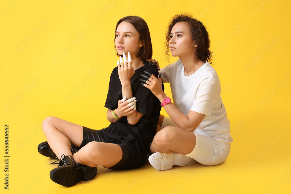 Beautiful women with painted fingers sitting on color background