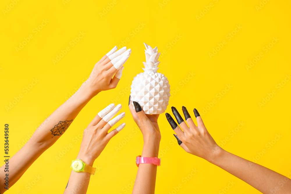 Female hands with hand watches, painted fingers and white pineapple on color background