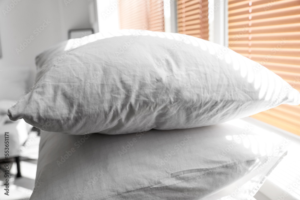 White pillows on shelf near window, closeup