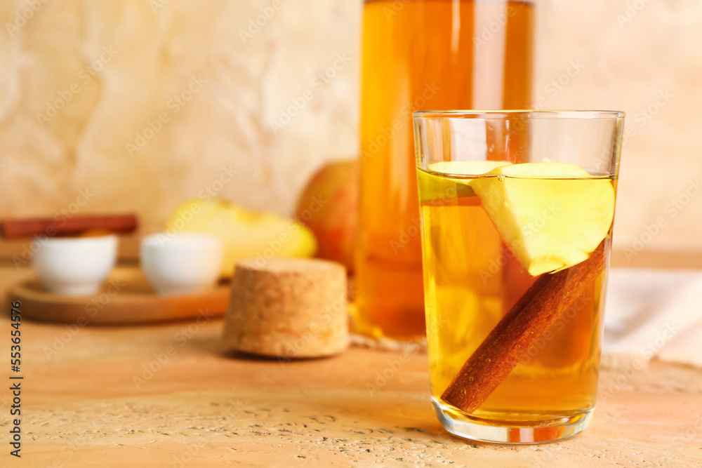 Glass of tasty apple juice on color table