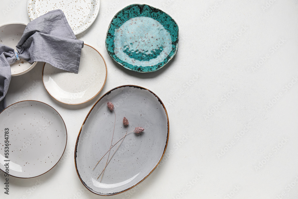 Different plates with floral decor and napkin on grey background