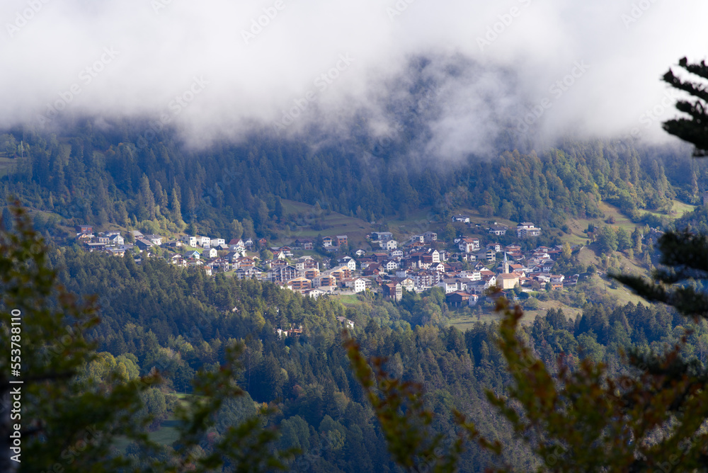 Scenic landscape at Anterior Rhine Valley with mountain village Trin, Canton Graubünden, on a blue c