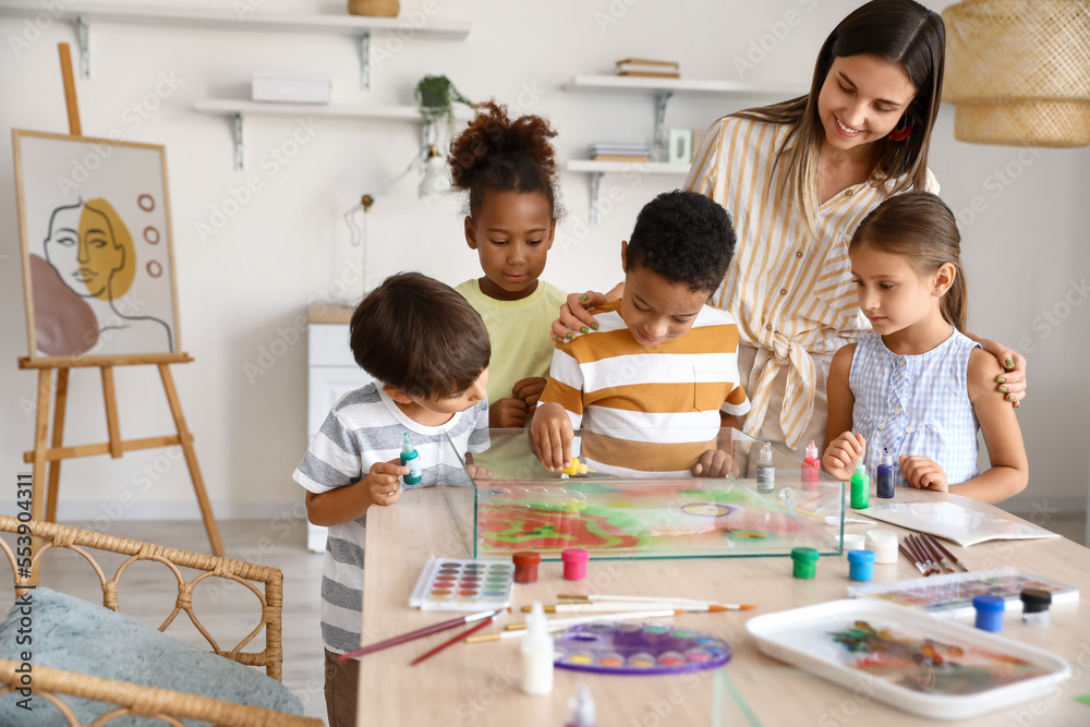 Little children with teacher during master class in Ebru painting at workshop