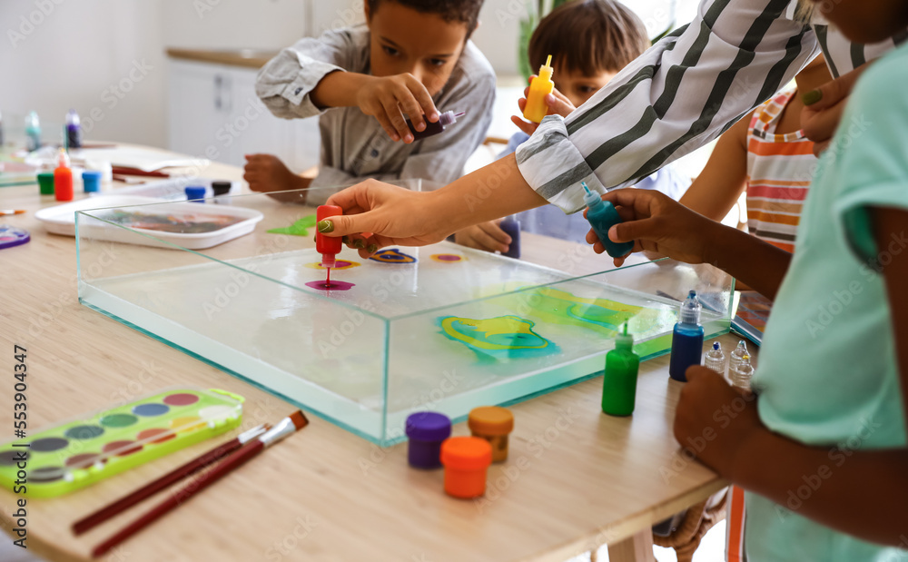 Little children with teacher painting on water during master class in Ebru