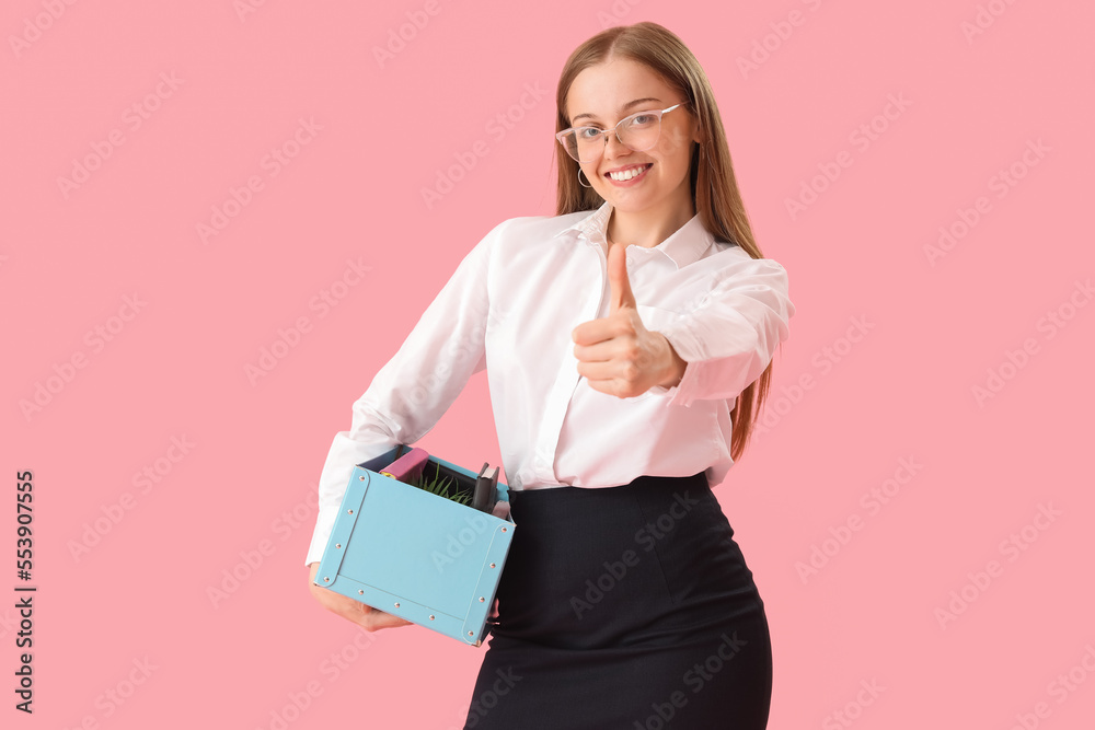 Fired young woman with personal stuff showing thumb-up on pink background