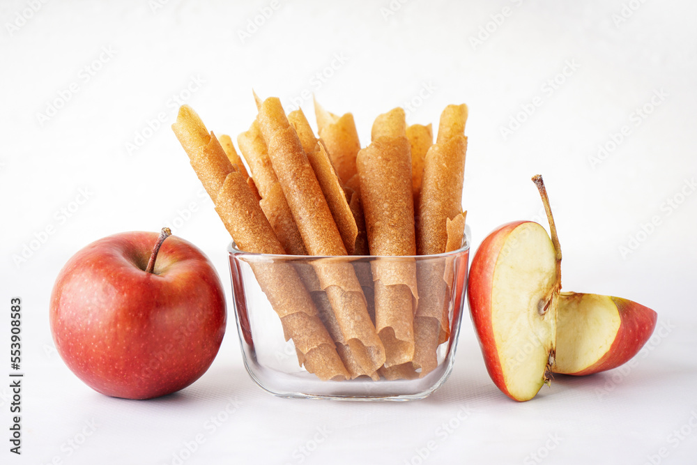 Glass bowl with tasty apple pastilles on light background