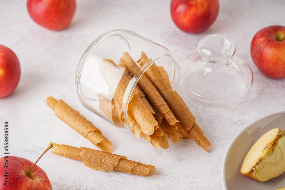 Glass jar with tasty apple pastilles on light background