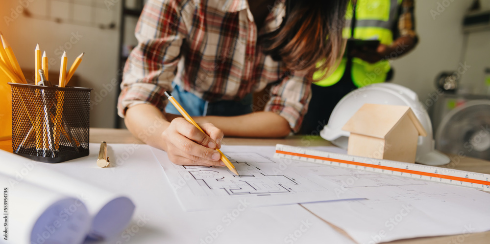 business woman hand working and laptop with on on architectural project at construction site at desk