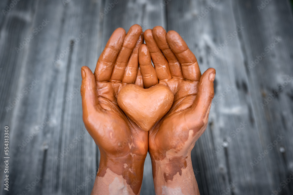 Heart made of potters clay in the hands of a master potter. Love concept