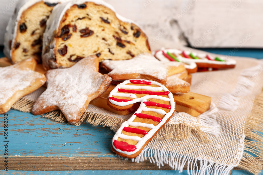 Board with tasty Christmas cookies and stollen on color wooden table, closeup