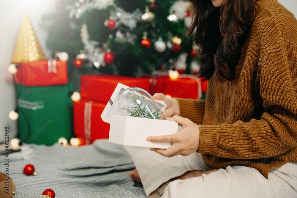 Merry Christmas Hands Hands opening christmas gift with red bow on background of christmas tree with