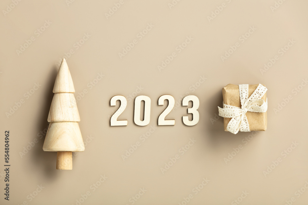 Natural color Christmas gift boxes and wooden Christmas tree on beige background, eco friendly trend