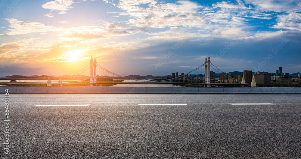 Asphalt road and bridge with city skyline at sunset in Zhoushan City, Zhejiang, China.